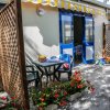 Un patio con tavolo, sedie, fiori e una tenda da sole a strisce gialle e bianche.