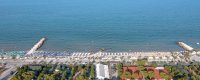 Vista aerea di una spiaggia con ombrelloni e mare calmo.