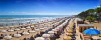 Spiaggia con lettini e ombrelloni, mare blu e cielo sereno.