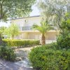 Edificio bianco con balconi, circondato da alberi e arbusti, all'esterno.