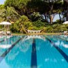Una piscina con corsie e sedie a sdraio tra alberi e palme.