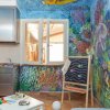 Stanza con pareti dipinte a tema marino, lavello, tavolo e giocattoli.