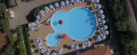 Piscina a forma irregolare vista dall'alto, circondata da ombrelloni bianchi e blu.
