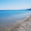 Una spiaggia di ciottoli bianchi con mare azzurro e cielo limpido.
