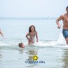 Una famiglia gioca nell'acqua al mare, sorridendo e correndo.