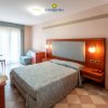 Camera d'hotel accogliente con letto matrimoniale, finestra e poltrona.
