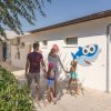 Famiglia cammina verso una struttura decorata con disegni di pesci.