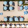 Veduta dall'alto di una spiaggia con ombrelloni blu e bianchi.