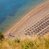 Spiaggia con ombrelloni disposti in file ordinate e poche persone che nuotano nell'acqua.