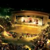 Anfiteatro all'aperto illuminato con pubblico.