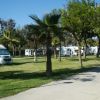 Area camper in un parco con alberi, erba verde e un cielo sereno.
