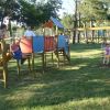 Bambini giocano in un parco con strutture di arrampicata e altalene.