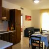 Cucina moderna con tavolo apparecchiato e divano in soggiorno luminoso.