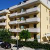 Edificio residenziale beige con balconi e auto parcheggiate davanti.