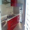 Cucina moderna con mobili rossi, piano cottura e frigorifero.