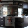 Cucina moderna con mobili scuri, piano cottura e lavello in acciaio.