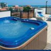 Una terrazza con jacuzzi blu e lettini, vista mare.
