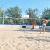Due persone giocano a beach volley in un campo sabbioso.