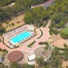 Vista aerea di un complesso con piscina, ombrelloni e anfiteatro.