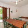 Soggiorno con tavolo, sedie verdi e porta finestra.