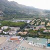 Veduta aerea di un paese costiero con montagne sullo sfondo.