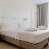 Letto matrimoniale con lenzuola bianche, due accappatoi, e applique bianche su testiera.