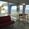 Sala con divano rosso, tavolo alto e vista mare attraverso grandi finestre.