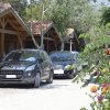 Due auto parcheggiate davanti a bungalow in legno in un'area alberata.